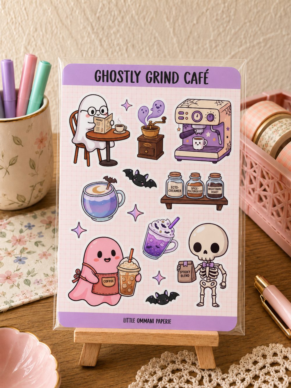 Ghostly Grind Café sticker sheet displayed on a wooden desk
